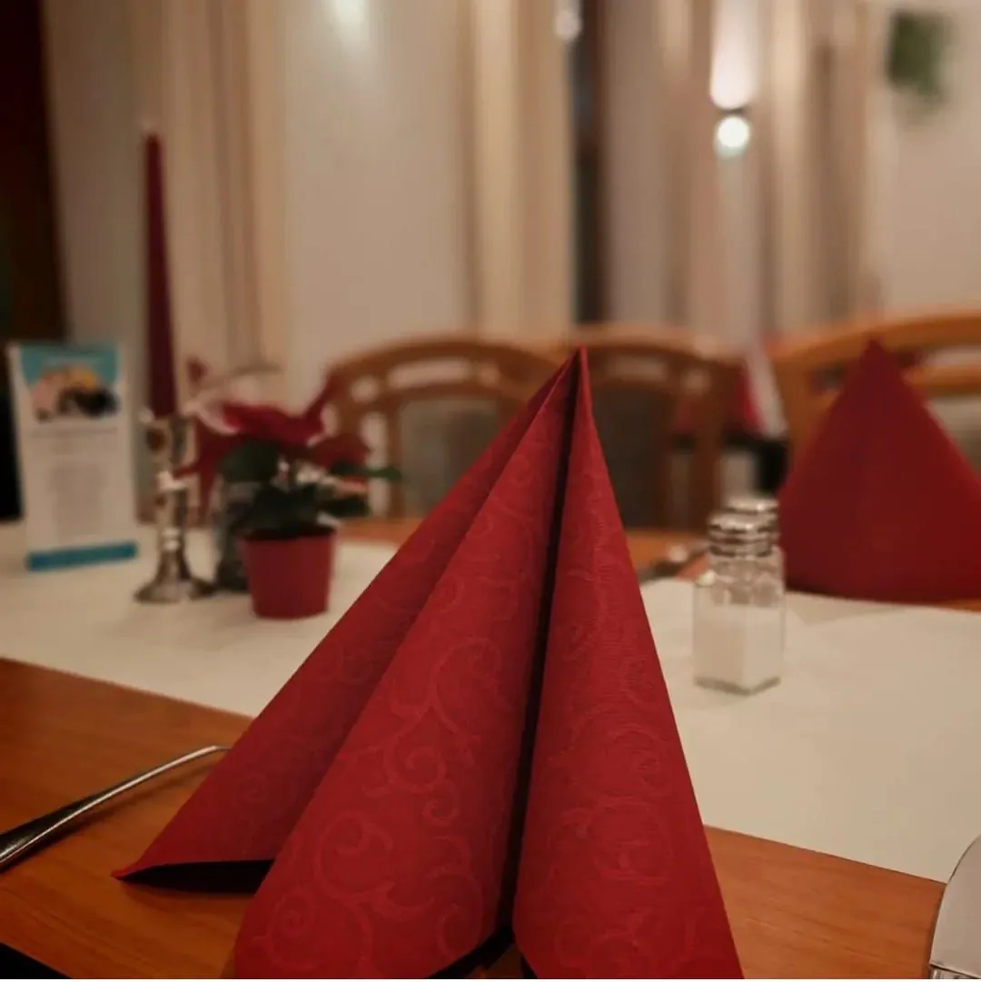 Eingedeckter Tisch im Restaurant – rote Servietten und Kerzenlicht